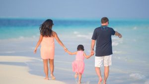 A joyful family walking hand in hand along a sunny beach, capturing moments of togetherness.